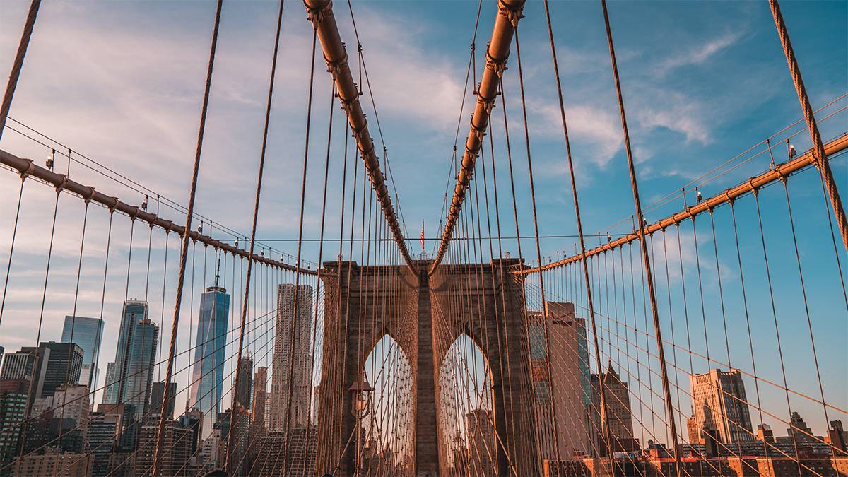 People walking and View of Flag on top of Brooklyn Bridge - NYC, New York, USA